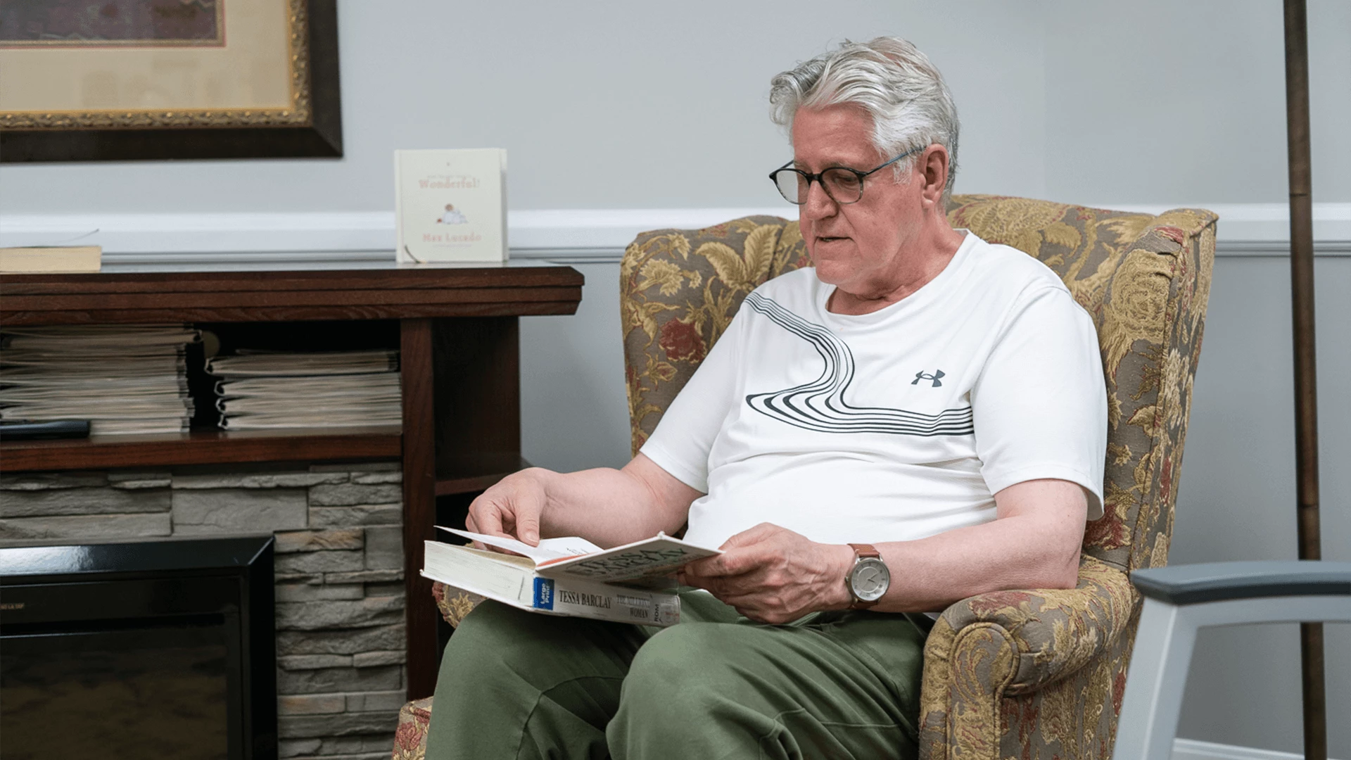 An elderly person reading a book while sitting on sofa
