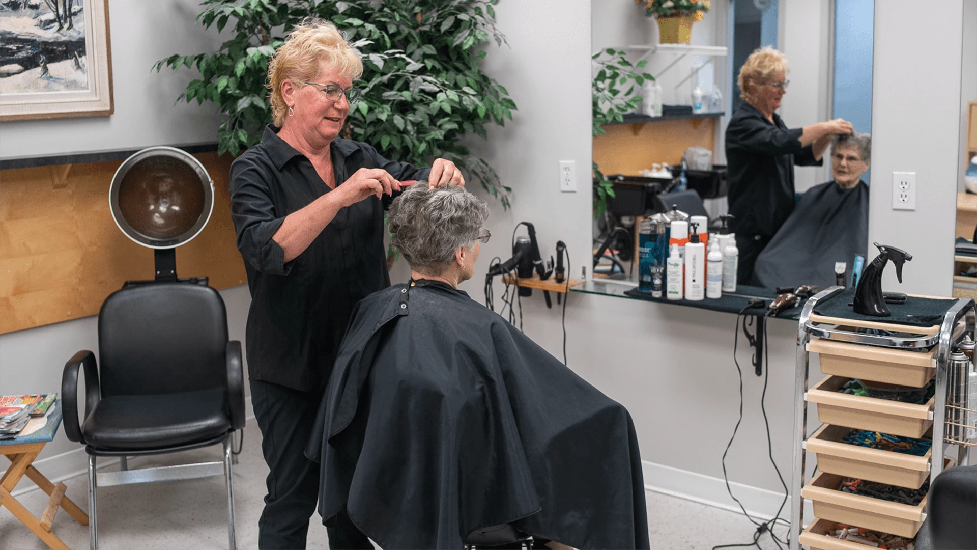 An elderly lady having hair cut in salon on site