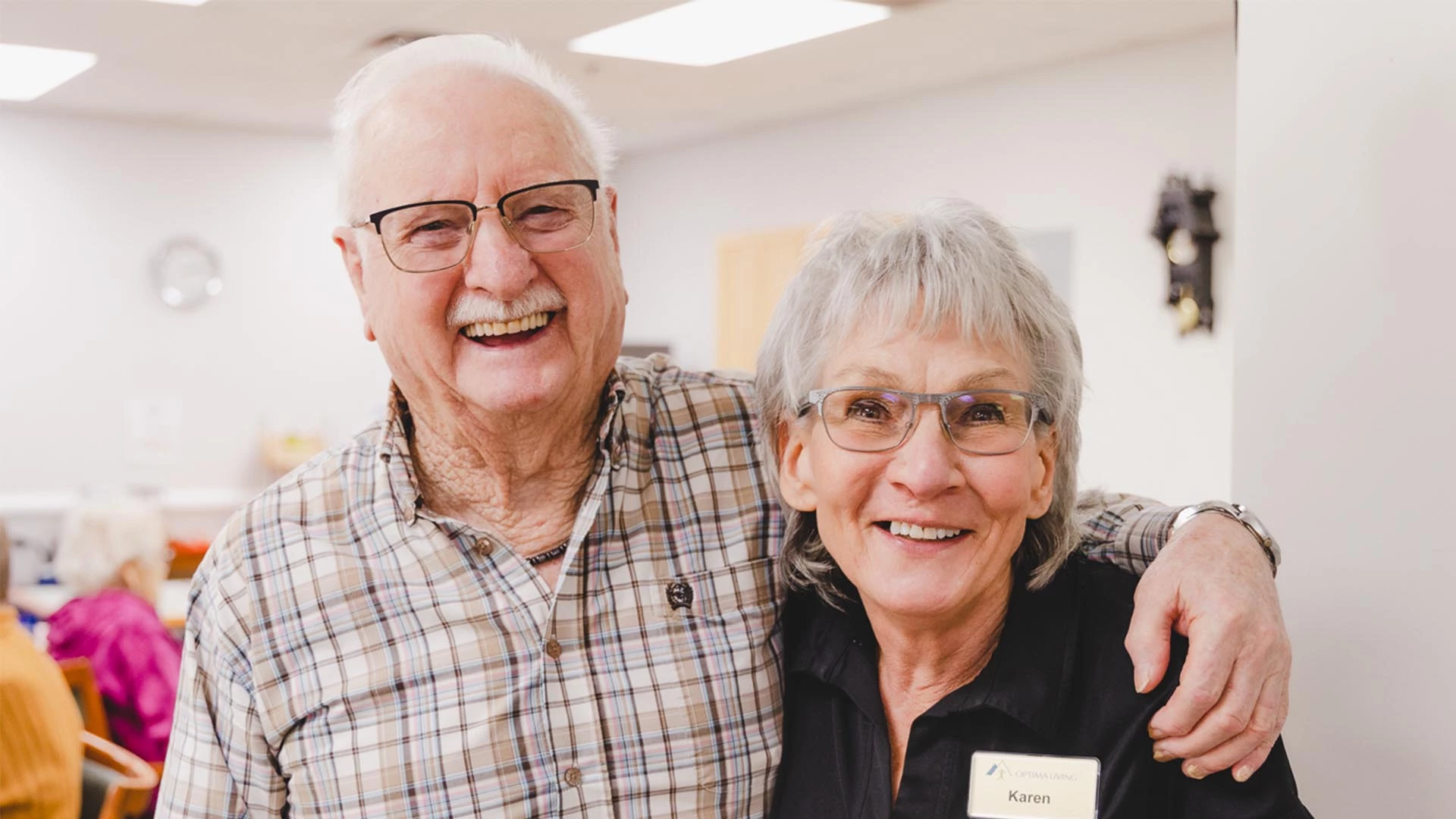 An elderly couple smiling with their arms around each other